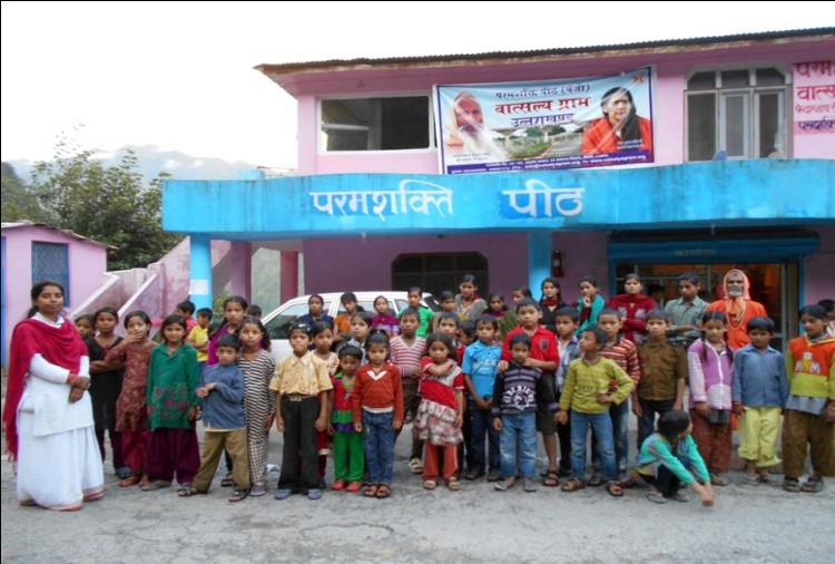 group of children and teacher standing outside of a building smiling for the camera