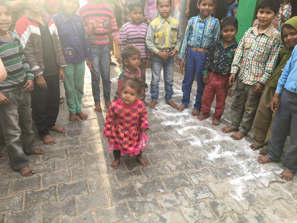 children standing barefoot in a circle with two little ones in the middle