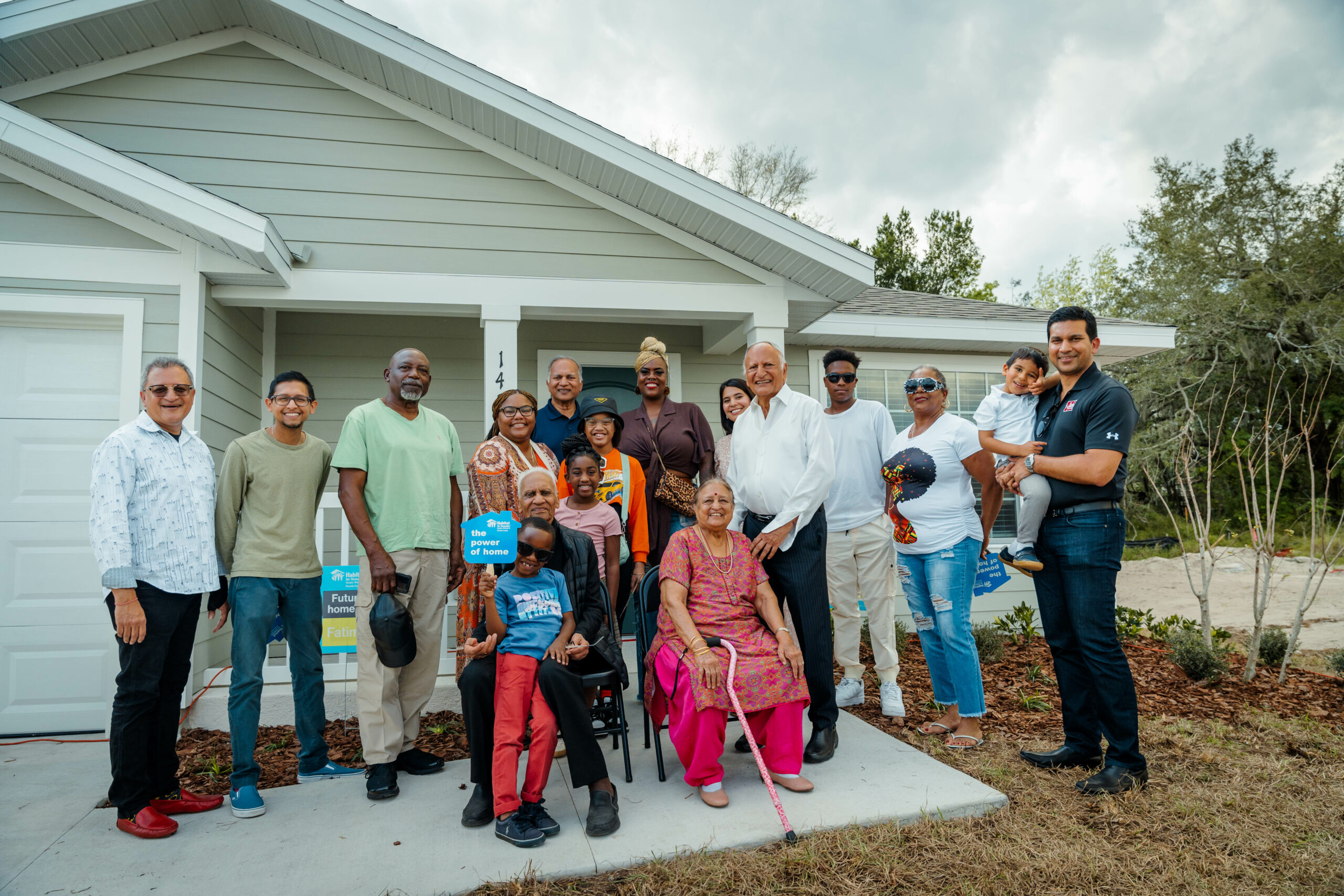 new homeowners and foundation members pose outside of a new home by Park Square Homes for Habitat for Humanity