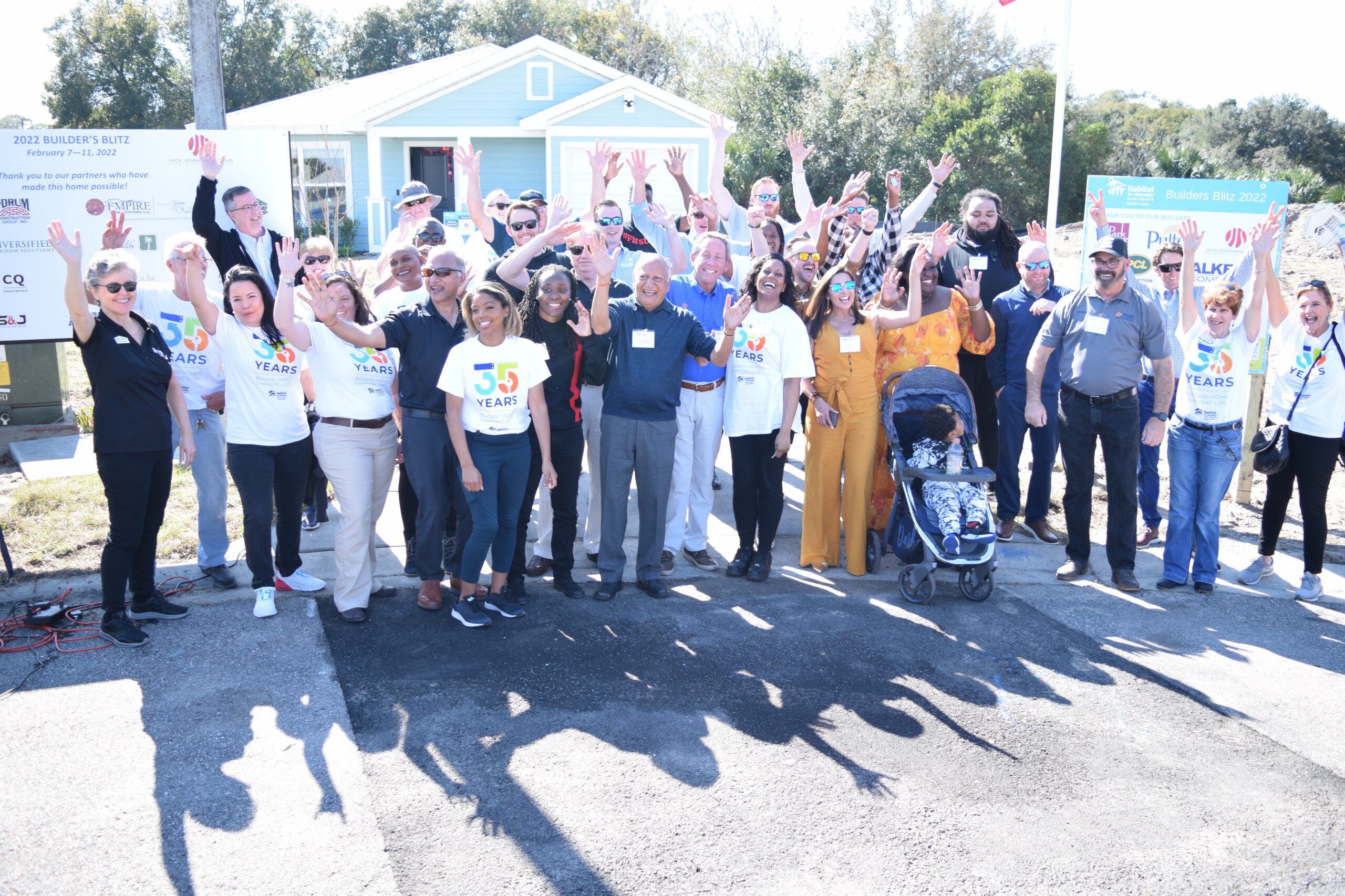 crowd raising hands and cheering outside of new homes for 2022 Park Square Homes and Habitat for Humanity builders blitz