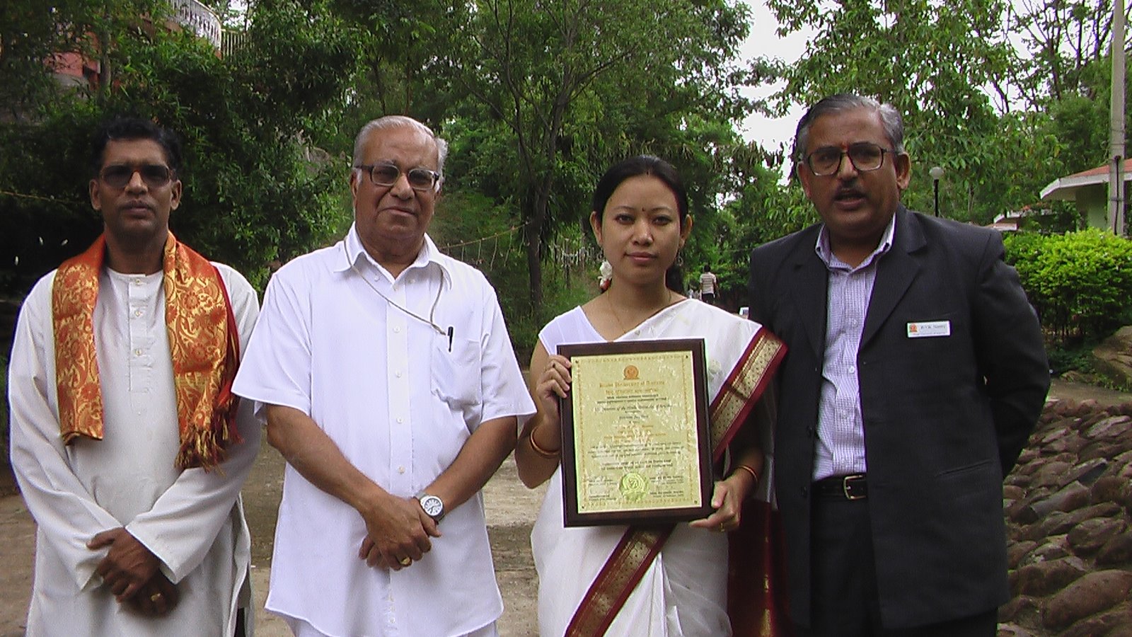 woman holds a certificate of education next to three men