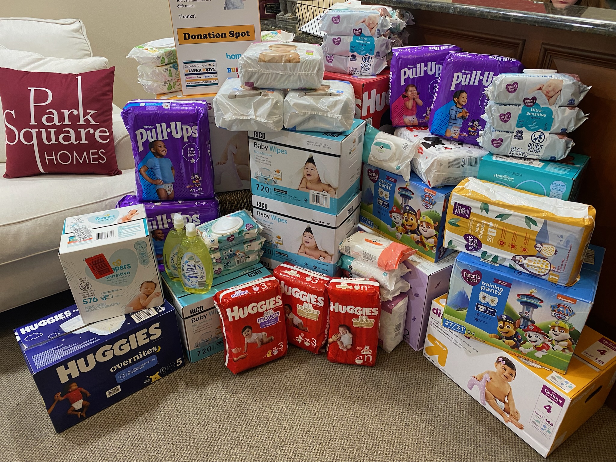 pile of new diaper boxes next to a Park Square Homes pillow