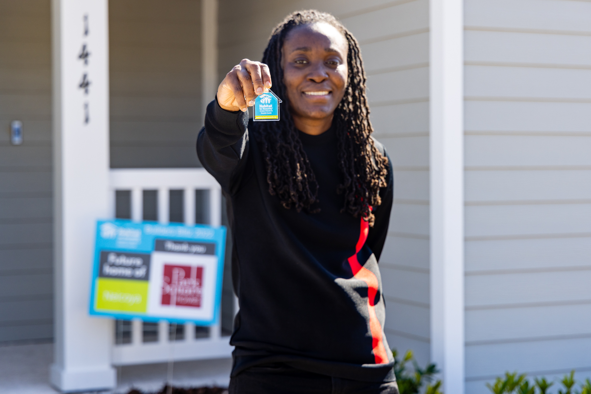 new homeowner holding a Habitat for Humanity house key up and smiling