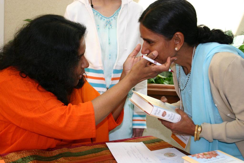 woman holds the face of another as she signs her book for her