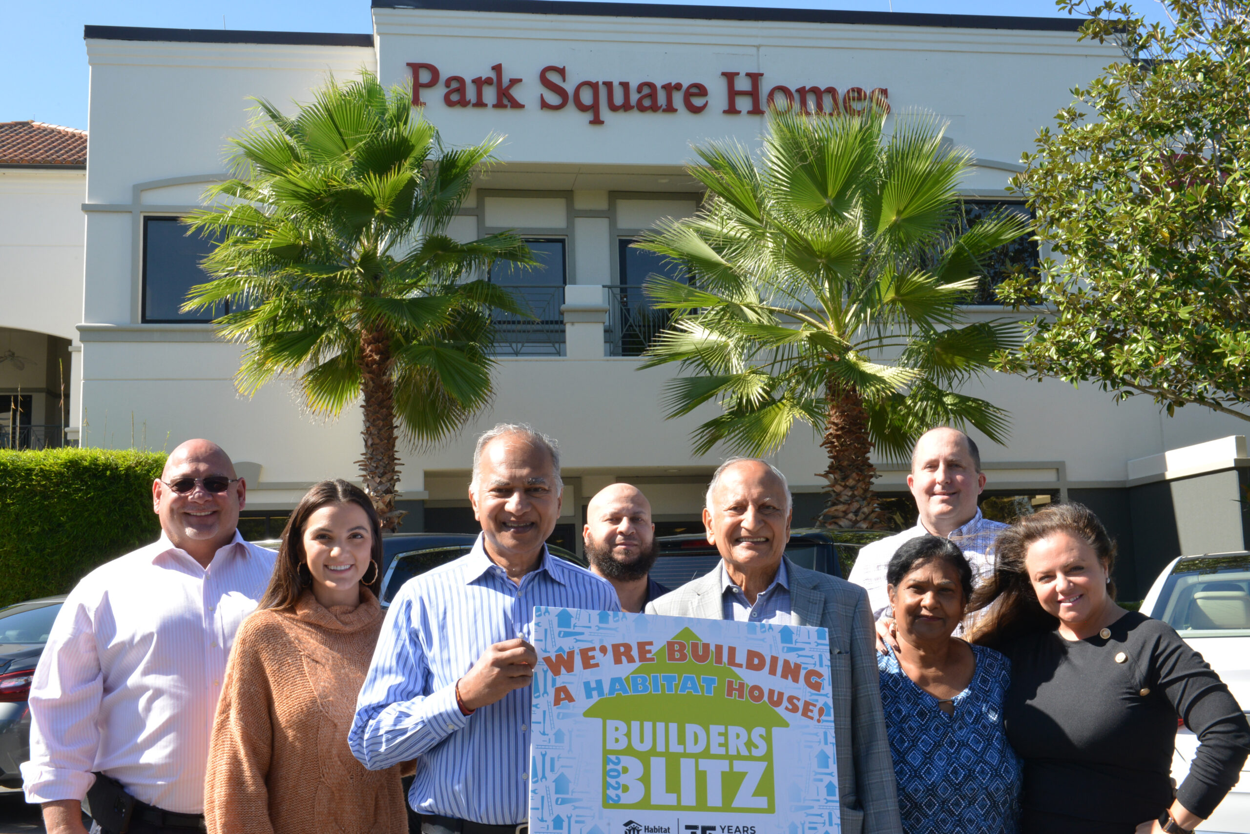 team members standing outside of the Park Square Homes building with 2022 Habitat for Humanity Builders Blitz sign.