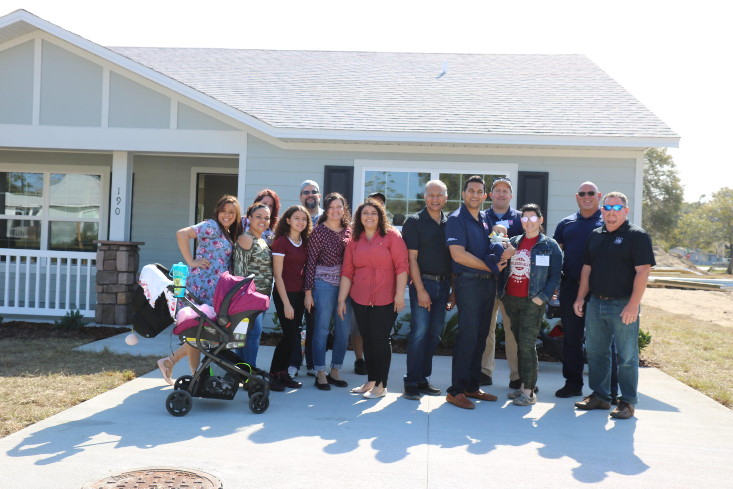 Park Square team members and families stand outside of a new home