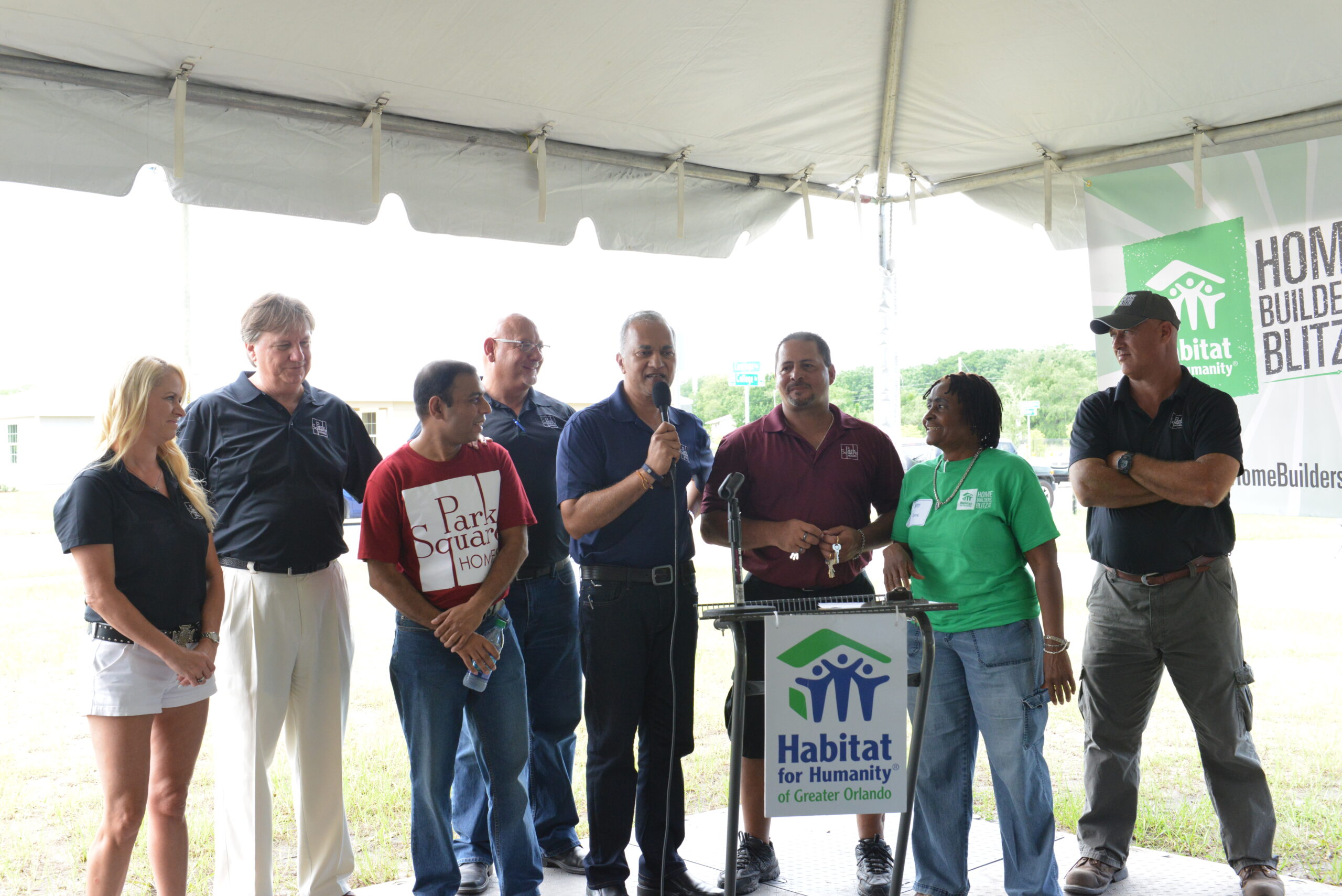 Suresh Gupta speaking under a tent for Park Square Homes at Habitat for Humanity Builders Blitz