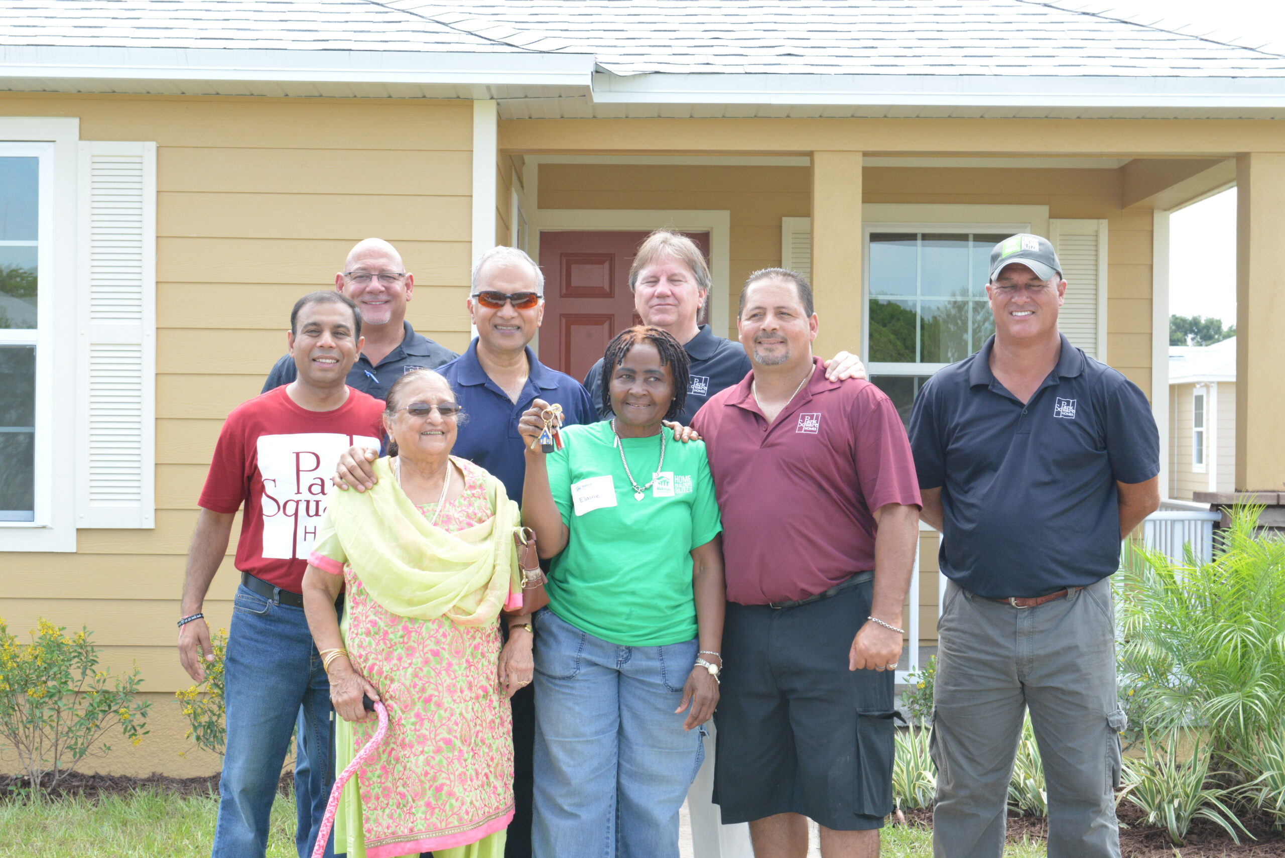 new homeowner and Park Square Homes team pose in front of a new home while holding up key