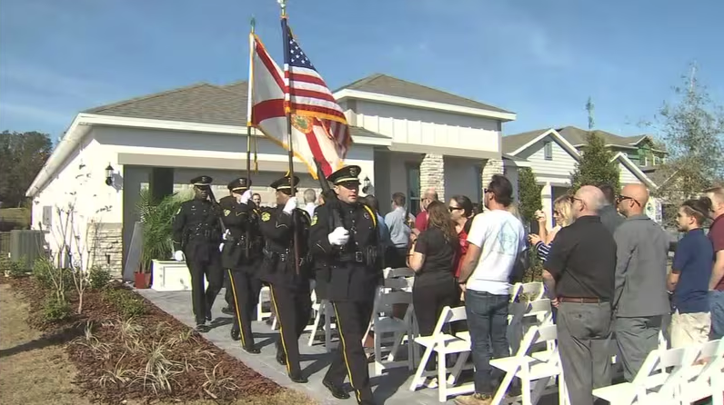 police with flags and crowd outside of a new home built by Park Square Homes for the Orlando Police Foundation